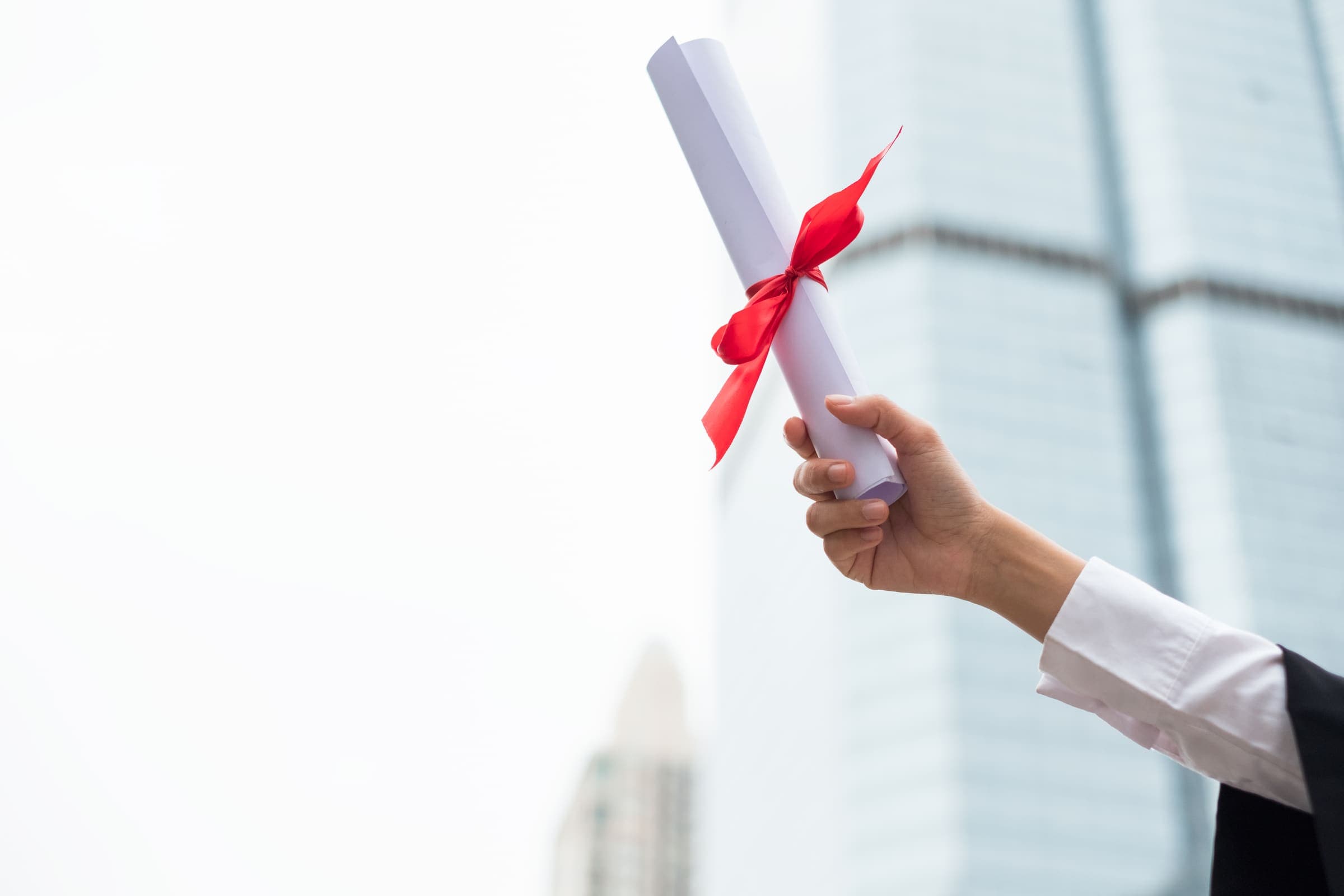 Successful graduate holding a diploma tied with a red ribbon