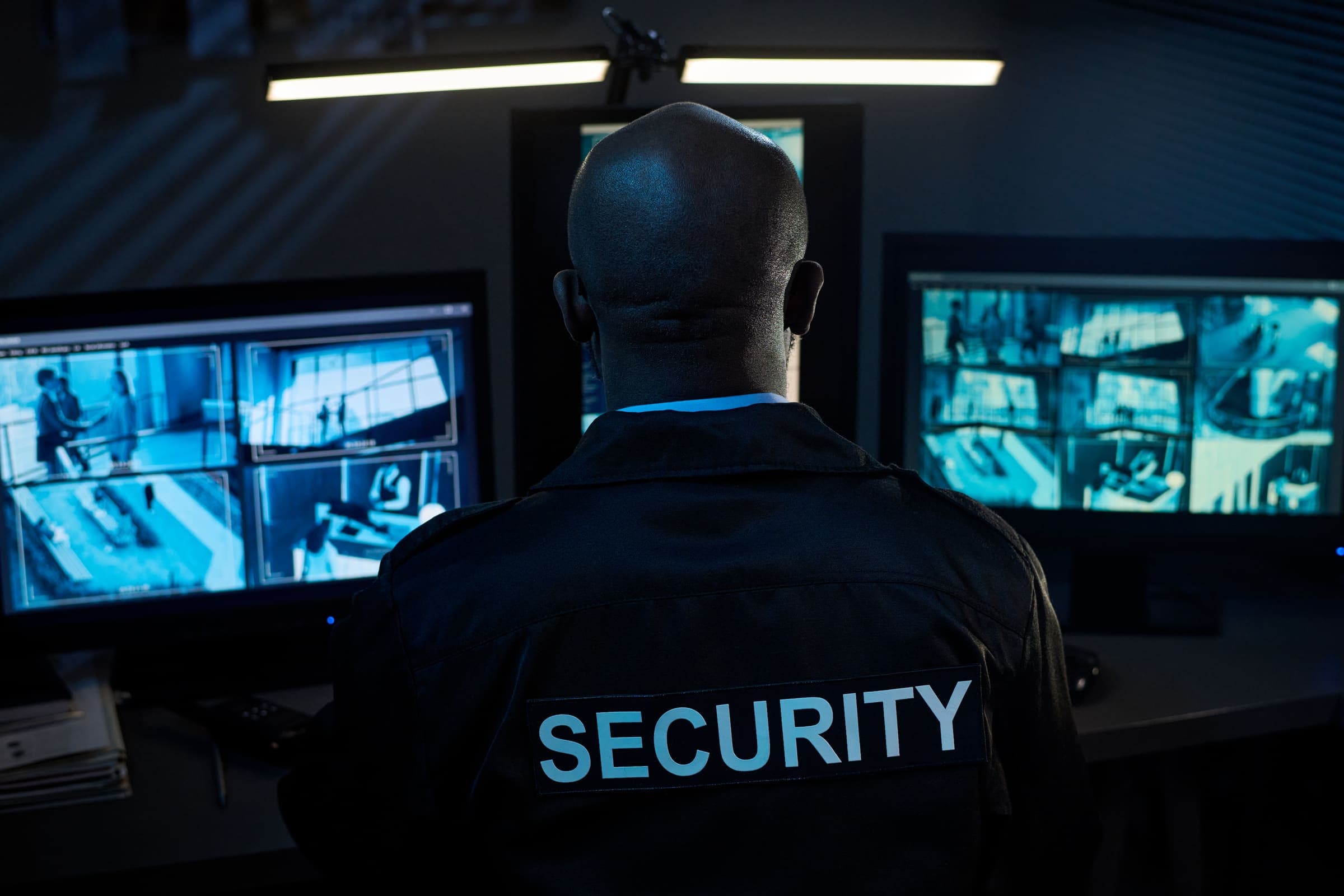 Security guard monitoring a bank of surveillance screens